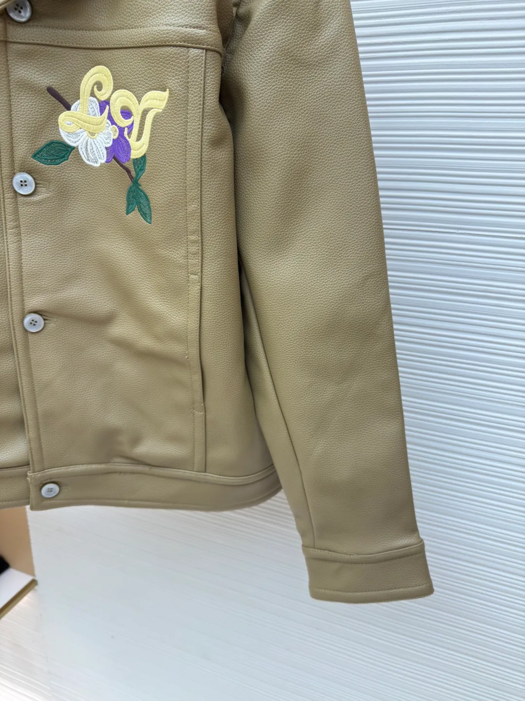 LOUIS VUITTON Tunic Jacket ●Authentic product: Purchased and developed by 50050 ●Item number: 1680165-C00 ●Fabric: Leather fabric ●Technology: Positioning cutting machine ●Version: Fitted version ●Weight: about 1365 grams ●Size: 50-52-54-56 ●Description: 24ss new tunic jacket has the retro connotation of gorgeous grain leather, with LV Flower Embroidery interprets seasonal tropical island elements. Marque L. Vuitton déposée leather patch sits at the back, and pearlescent buttons add a chic touch. The overall workmanship is very complicated. The embroidery is made with heat-capacitive glue, which needs to be ironed to ensure quality. The checkerboard pattern needs to be positioned correctly, so it is very fast. Each process of the entire garment is slow and time-consuming.